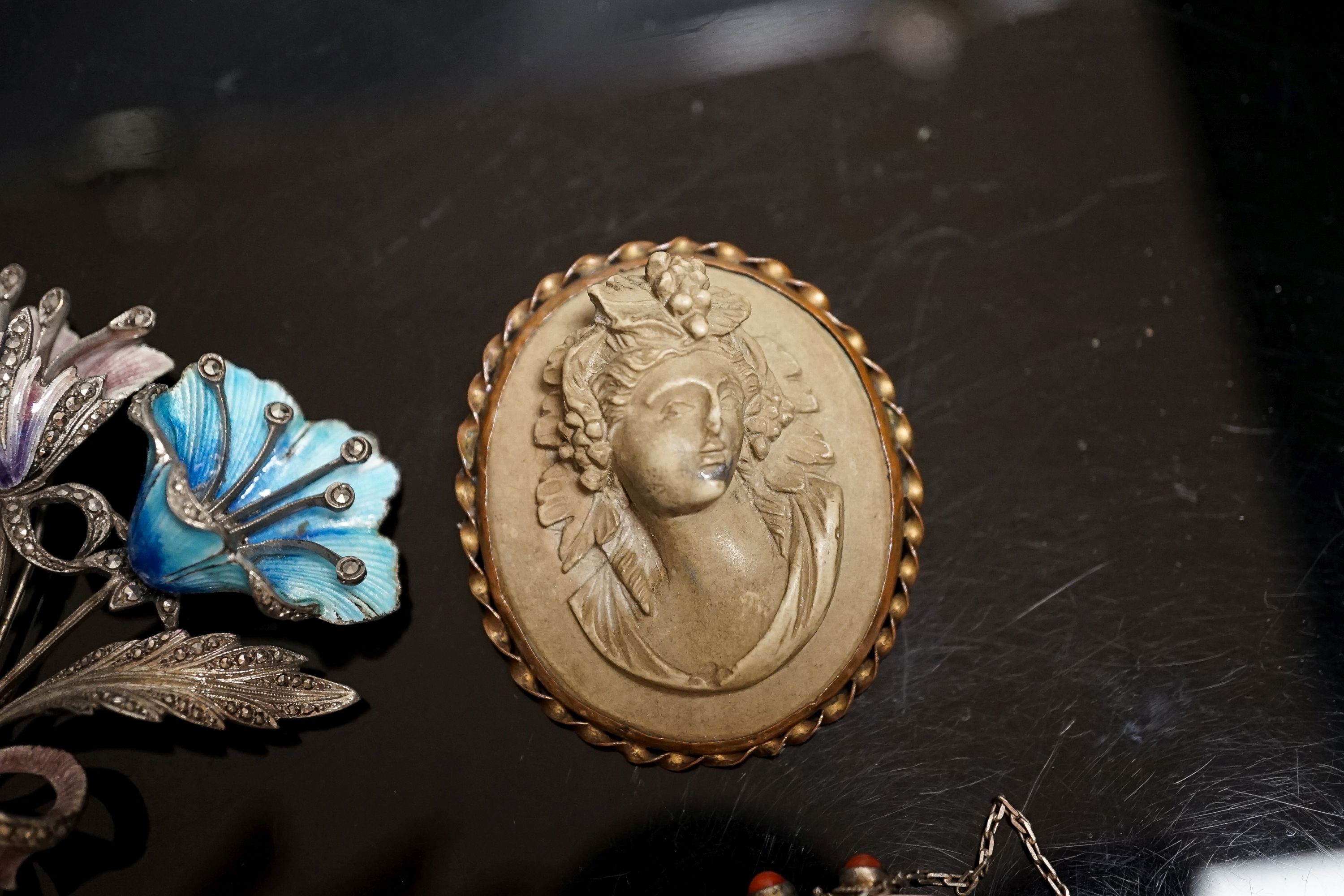 A 19th-century Lava cameo brooch, 49mm, a marcasite and enamel floral spray brooch and a coral mounted white metal bracelet.